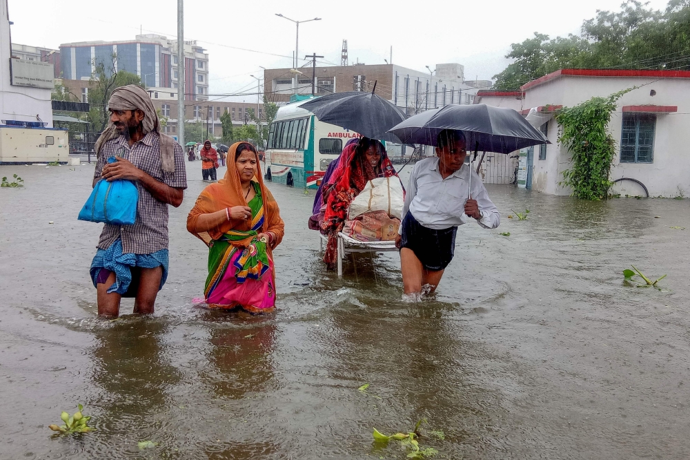 Patients wade through floodwaters on their way to hospital during heavy monsoon rain in Patna in the northeastern state of Bihar on September 28, 2019. / AFP / Sachin KUMAR 