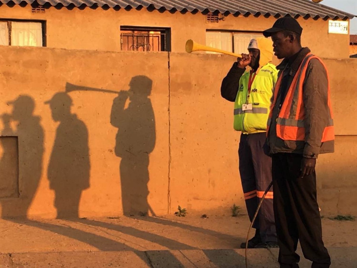 The shadows of Isaac Makhubo and Paul Themba blowing vuvuzela trumpets silhouette against a wall in in Johannesburg, South Africa on 19 September, 2019. Thomson Reuters Foundation/Kim Harrisberg