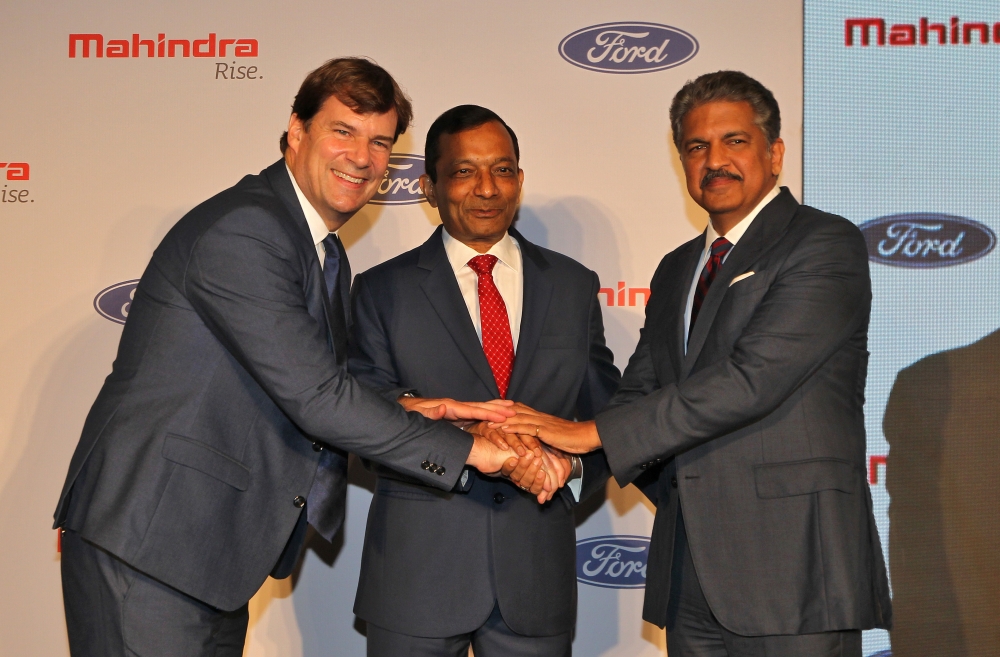 Jim Farley, President of Ford New Businesses, Technology & Strategy, Pawan Goenka, Managing Director of Mahindra & Mahindra Limited, and Anand Mahindra, Chairman of Mahindra Group, join their hands after attending a news conference in Mumbai, India, Octob