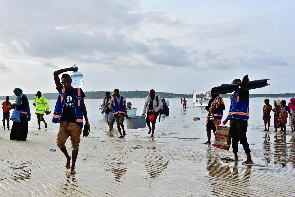 Staff and volunteers of Safari Doctors carry medical supplies to shore as they arrive to conduct a mobile clinic at Kiangwe in Lamu on June 17, 2019.  AFP / Tony Karumba 