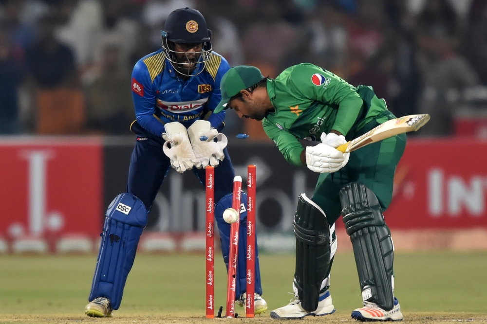 Pakistan's captain Sarfraz Ahmed (R) is bowled out as Sri Lanka's wicketkeeper Minod Bhanuka looks on during the second Twenty20 International cricket match between Pakistan and Sri Lanka at the Gaddafi Cricket Stadium in Lahore on October 7, 2019. (AFP /