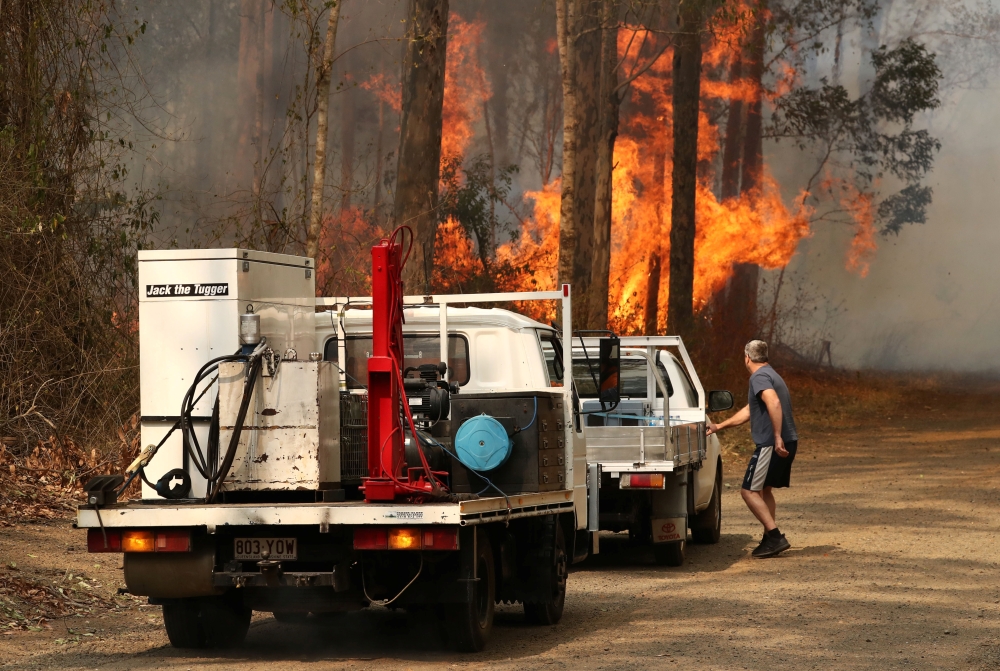 A local resident is seen near a bushfire burning next to Busbys Flat Road in Busbys Flat, northern NSW, Australia, October 9, 2019. AAP Image/Jason O'Brien/via REUTERS
