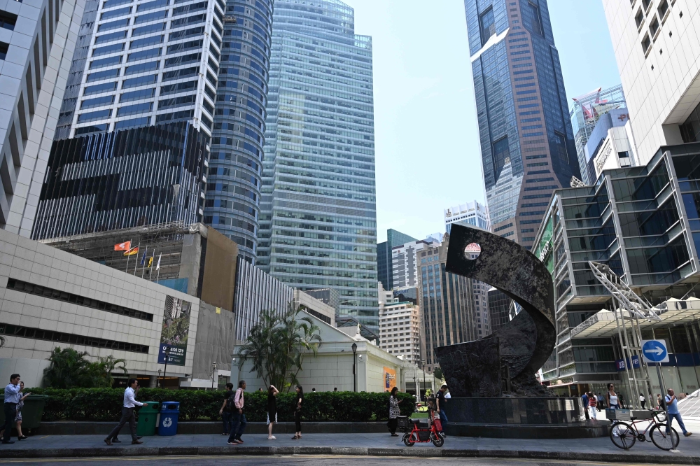 People walk past buildings in the financial business district of Raffles Place in Singapore on October 14, 2019. AFP / Roslan RAHMAN