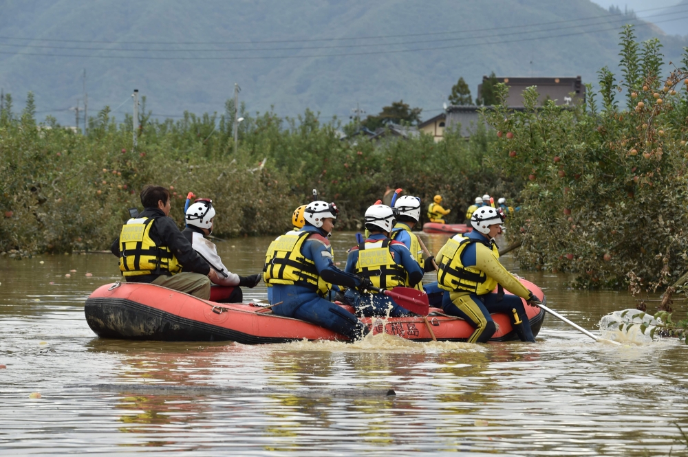 Emergency personnel paddle across floodwaters using an inflatable raft during search and rescue operations in the aftermath of Typhoon Hagibis, in Nagano on October 14, 2019. AFP / Kazuhiro NOGI