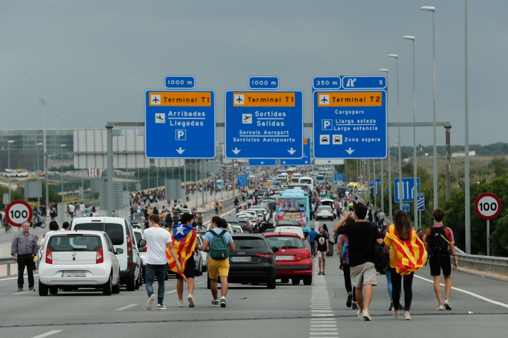 People walk on the highway towards El Prat airport in Barcelona on October 14, 2019 as thousands of angry protesters took to the streets after Spain's Supreme Court sentenced nine Catalan separatist leaders to between nine and 13 years in jail for seditio