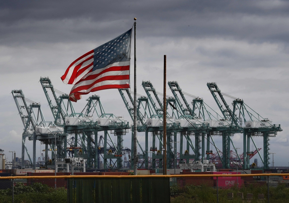 In this file photo taken on March 04, 2019 the US flag flies over shipping cranes  in Long Beach, California. AFP / Mark Ralston  