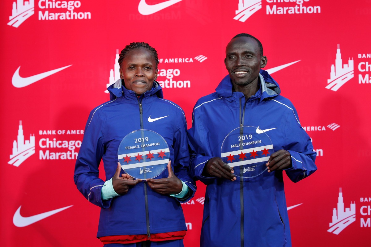 Kenya's Brigid Kosgei (L) smiles after winning the women's 2019 Bank of America Chicago Marathon with the World Record, next to the men's winner Kenya's Lawrence Cherono (R) on October 13 2019 in Chicago, Illinois. AFP / Kamil Krzaczynski