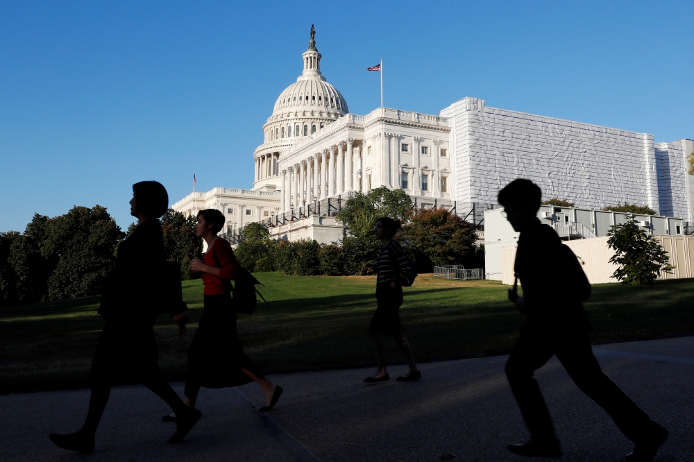 People walk past the U.S. Capitol Building in Washington, U.S., October 15, 2019. REUTERS/Carlos Jasso
 