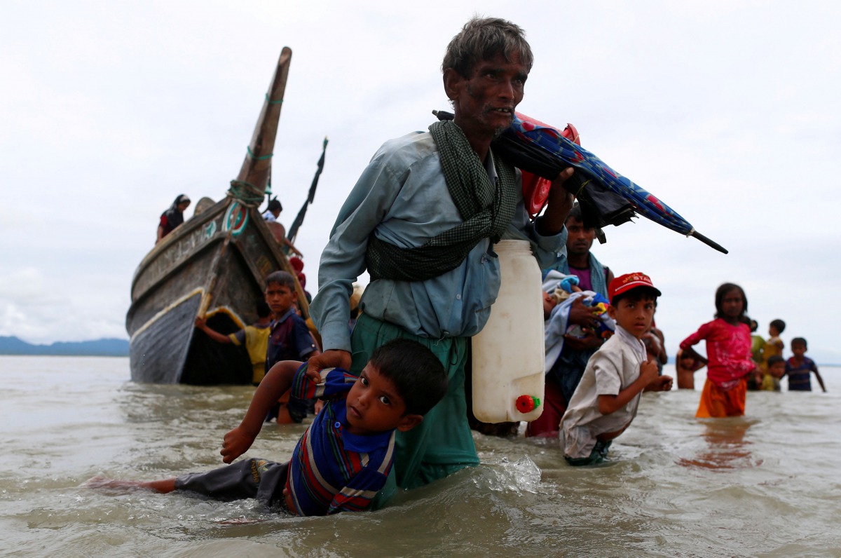 A Rohingya refugee pulls a child as they walk to the shore after crossing border by boat through the Bay of Bengal in Shah Porir Dwip, Bangladesh, September 10, 2017. Reuters / Danish Siddiqui