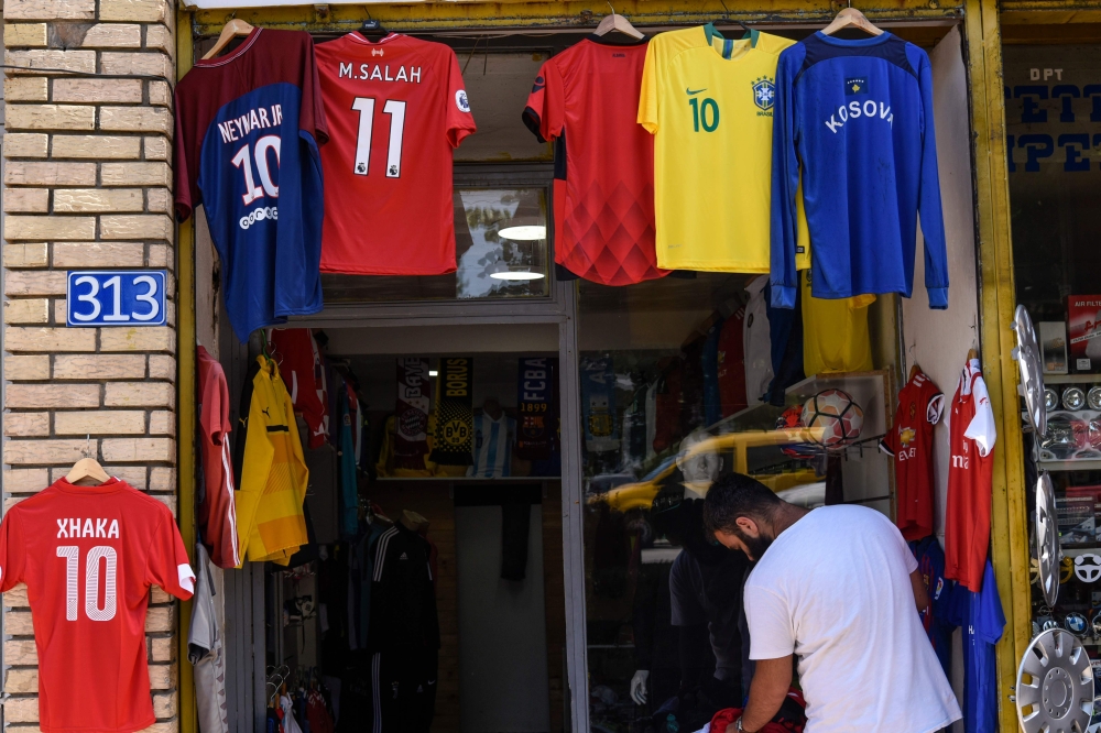 Kosovo Albanian pedestrian walking past a replica football jersey of Switzerland midfielder Granit Xhaka outside a shop in the Kosovo capital Pristina on June 18, 2018. AFP / Armend Nimani