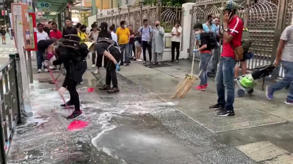 People and protesters help cleaning up the blue dye that stained steps of the Kowloon Masjid and Islamic Centre in Hong Kong October 21, 2019 in this still image obtained from social media video. Broadcast News Network/Hong Kong Baptist University via REU