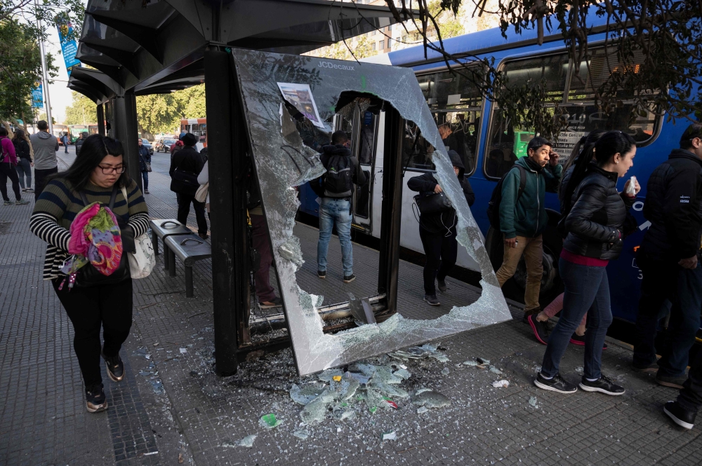 People wait to take a bus in Santiago, Chile on October 21, 2019.  AFP / Pedro Ugarte
