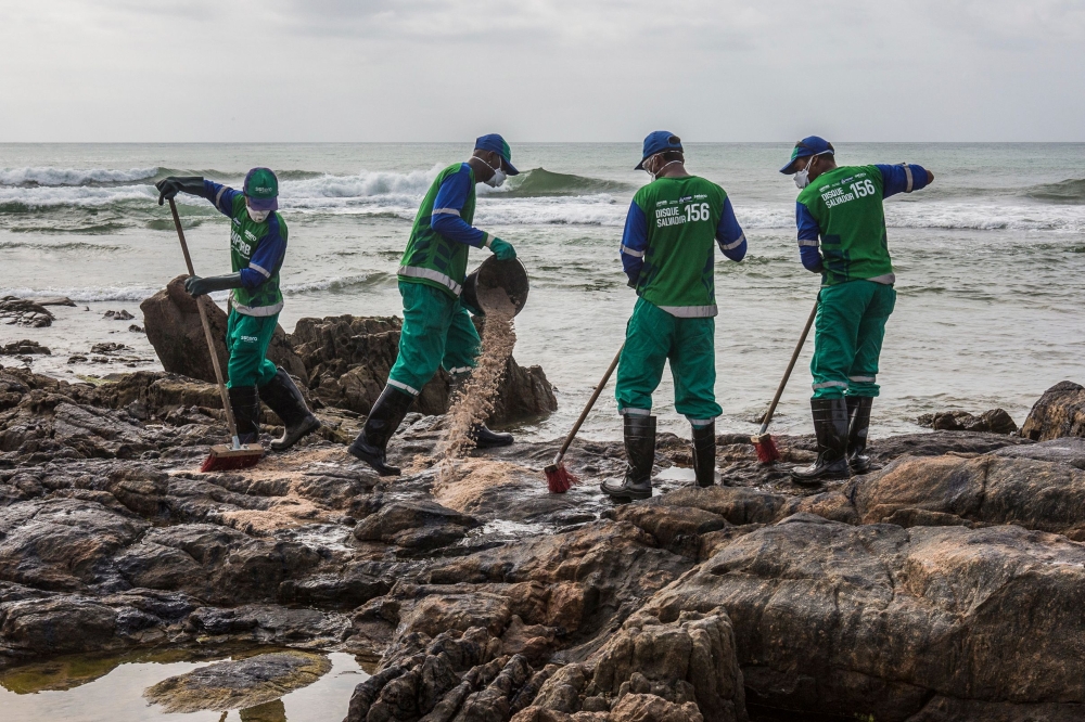 Municipal workers remove spilled crude oil at Pedra do Sal beach in Salvador, Bahia state, Brazil, on October 23, 2019.  AFP / Antonello Veneri 