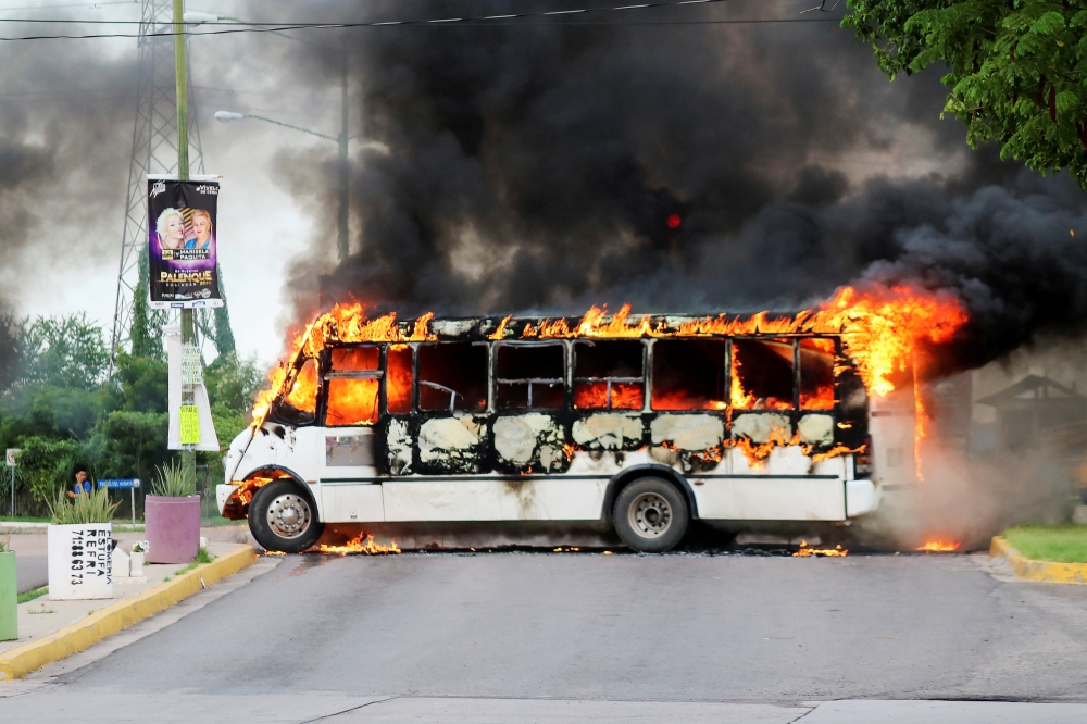 FILE PHOTO: A burning bus, set alight by cartel gunmen to block a road, is pictured during clashes with federal forces following the detention of Ovidio Guzman, son of drug kingpin Joaquin 