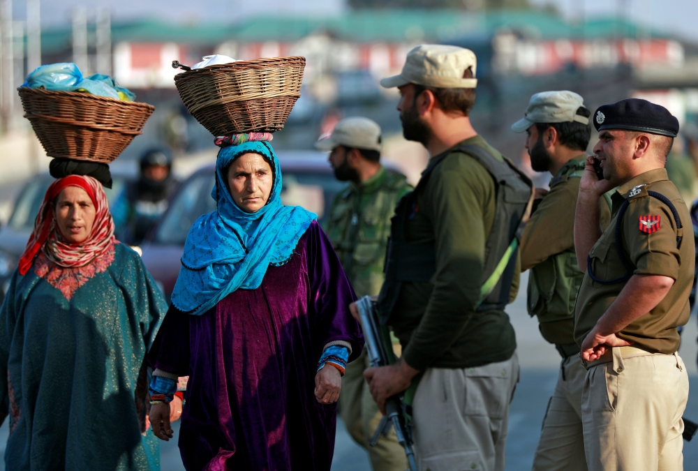 Kashmiri women walk past Indian policemen standing guard in a street in Srinagar October 31, 2019. Reuters/Danish Ismail