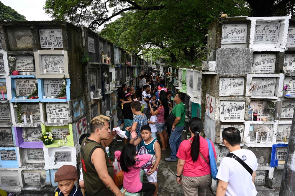 People light candles and pray for their relatives at a cemetery during the annual observance of All Saint's Day in Manila on November 1, 2019. Millions of Filipinos flocked to cemeteries to visit and pray at the graves of their loved ones to mark the holi