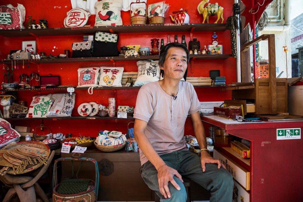 This photo taken on June 6, 2019 shows shopkeeper Louis To posing for a photo at his shop on Cheung Chau Island in Hong Kong. AFP / Isaac Lawrence 