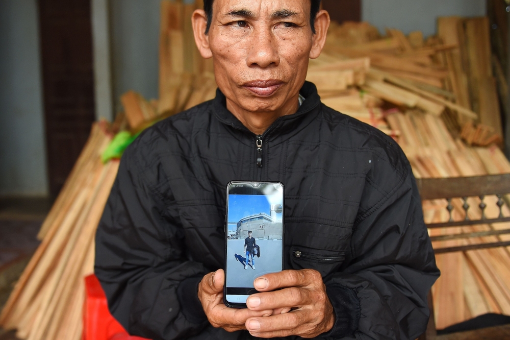 Nguyen Dinh Gia, father of 20-year-old Nguyen Dinh Luong who is feared to be among the 39 people found dead in a truck in Britain, poses with his son's photograph at their house in Can Loc district of Vietnam's Ha Tinh province on October 29, 2019.  AFP /