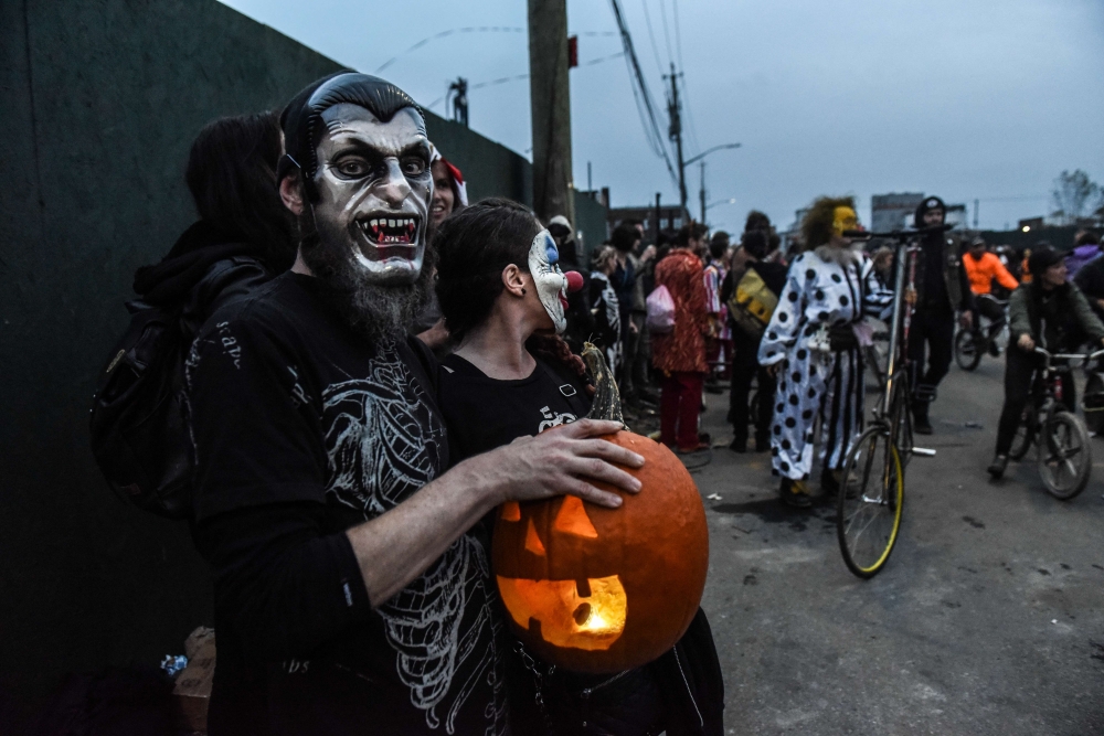  A man poses with a pumpkin while people in costume ride bicycles during the annual Bike Kill event on October 26, 2019 in New York City.  Stephanie Keith/Getty Images/AFP
