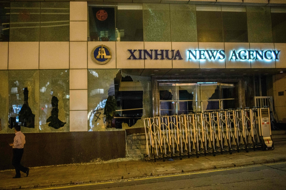 A pedestrian walks past China's Xinhua News Agency, after it was damaged by protesters, in Hong Kong on November 2, 2019. AFP / Anthony WALLACE