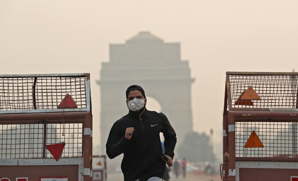 A man wearing a mask runs past the India Gate on a smoggy morning in New Delhi, India, October 28, 2019 REUTERS