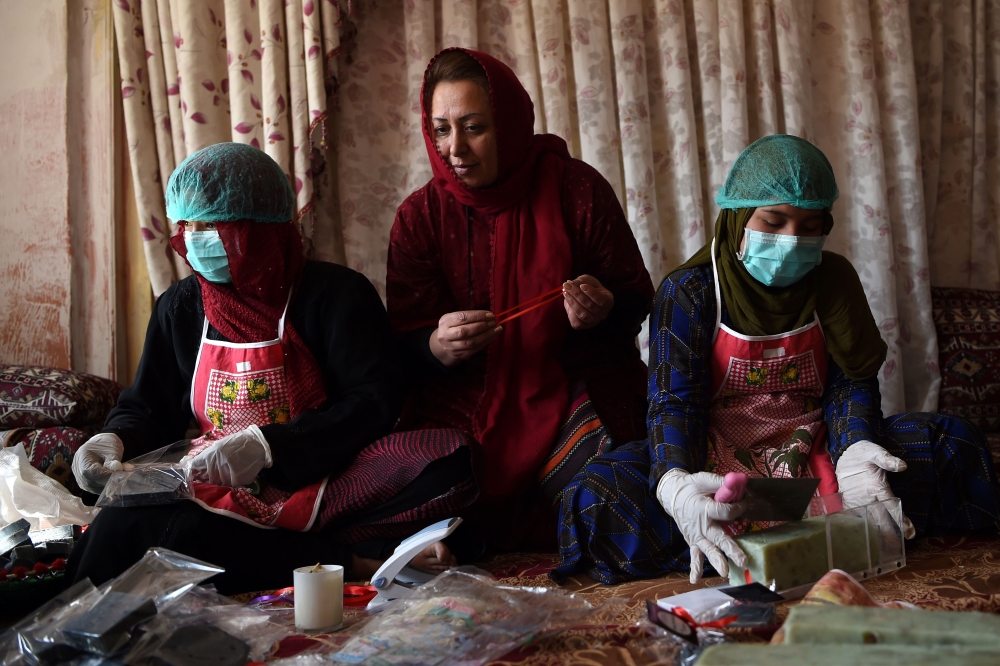 In this photo taken on October 8, 2019, Afghan entrepreneur Marghuba Safi (C) sits with female workers arranging bars of soap at her organic skin care company in Kabul.  AFP / Wakil Kohsar