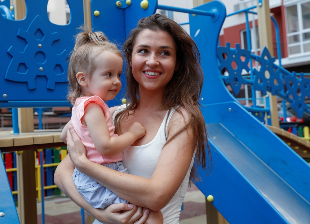 Olena Kudryashova and her daughter Maya smile before an interview with Reuters at a playgroung in Kiev, Ukraine August 12, 2019. Reuters/Valentyn Ogirenko
 