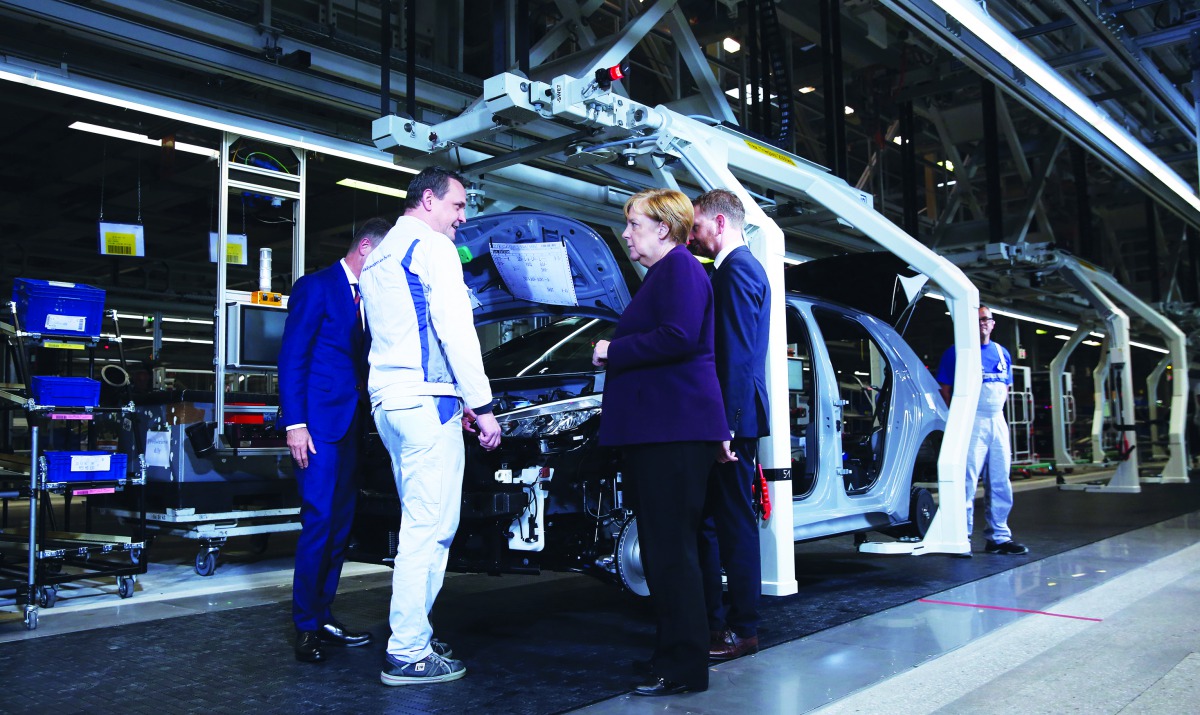 German Chancellor Angela Merkel talks with an employee as she visits VW's car factory in Zwickau, eastern Germany, on November 4, 2019 on the occasion of the start of the production of the new Volkswagen electric car, the ID.3 model. AFP / Ronny Hartmann