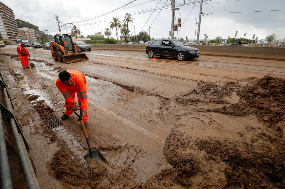 Workers remove mud from the N-11 road after floods caused by torrential rain north of Barcelona, Spain, Oct. 23, 2019. Reuters/Albert Gea