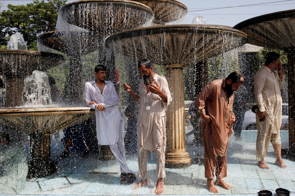 Men cool off from the heatwave as they shower at a water fountain along a road in Karachi, May 25, 2018. Reuters /  Akhtar Soomro