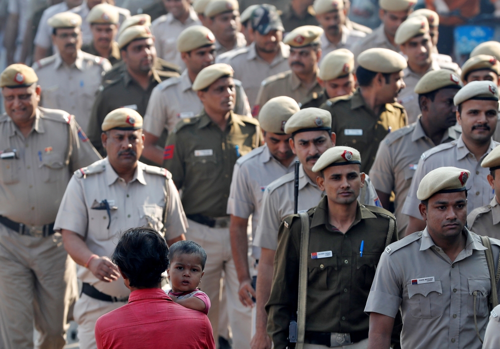 A man carries a child as police officers conduct a flag march in a street outside Jama Masjid, before Supreme Court's verdict on a disputed religious site claimed by both majority Hindus and Muslim in Ayodhya, in the old quarters of Delhi, India, November
