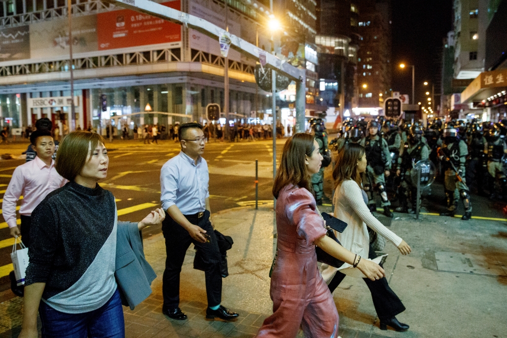 Locals pass police in riot gear during a standoff with protesters in Mong Kok, after Chow Tsz-lok, 22, a university student, died after he fell during a protest, at Tseung Kwan O, Hong Kong, China November 8, 2019.  REUTERS/Thomas Peter