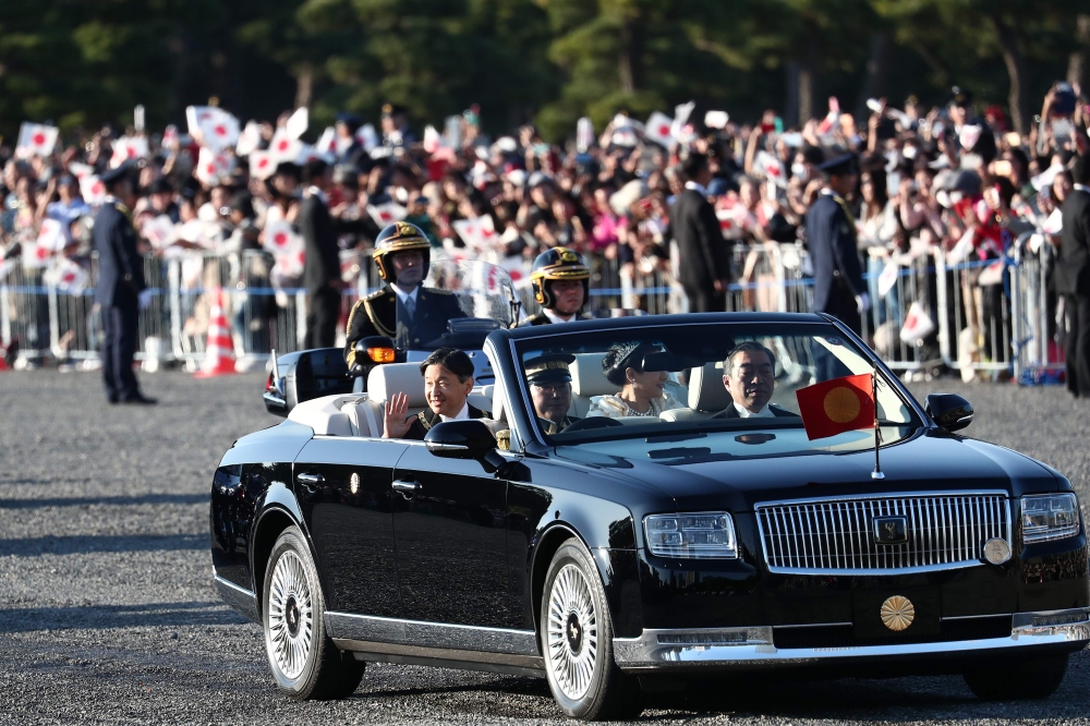 Japan’s Emperor Naruhito (L) and Empress Masako (R) wave during a royal parade in Tokyo on November 10, 2019. / AFP / Behrouz MEHRI