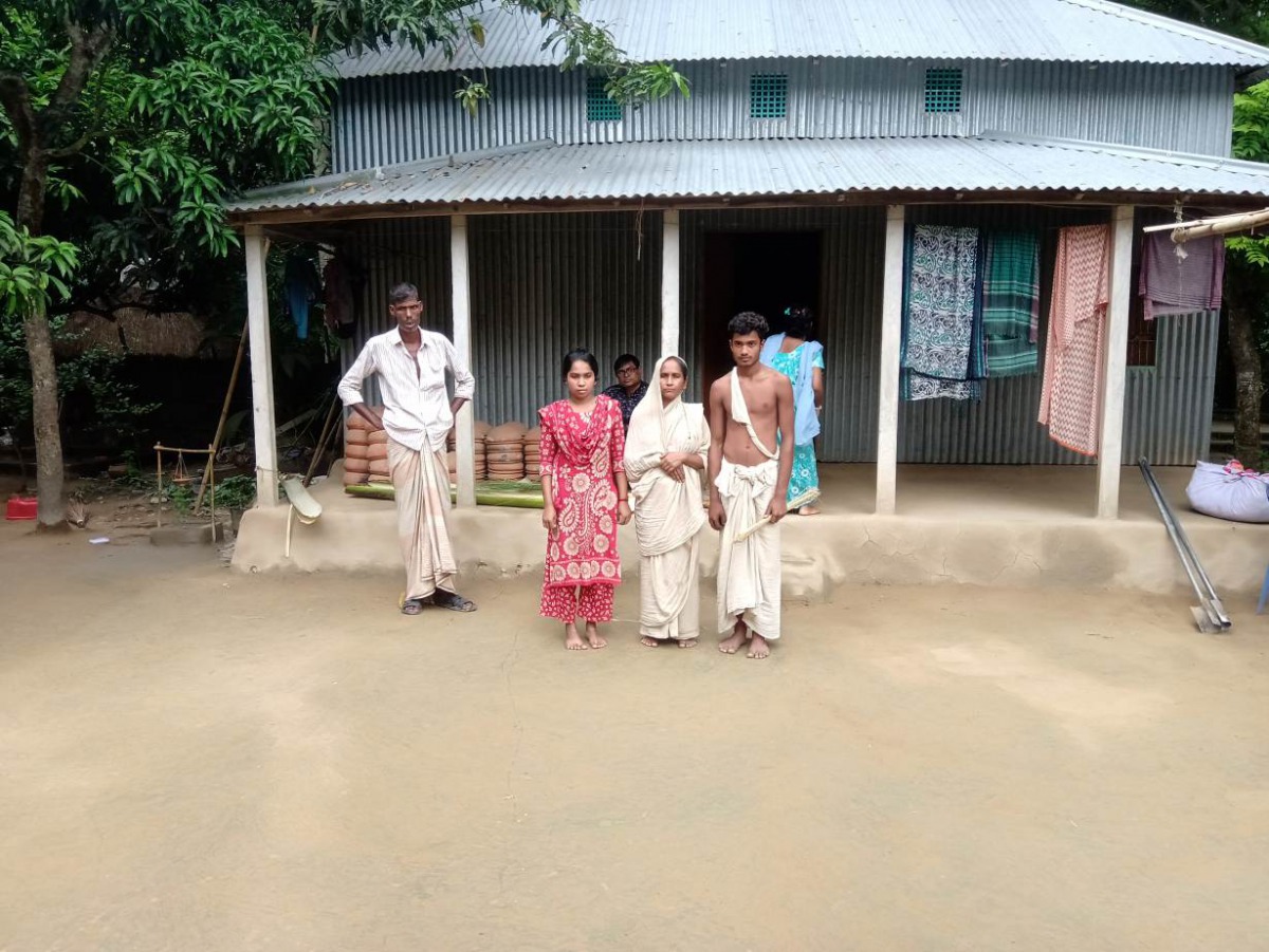 A view of the widow of Mongol Chandra Sarker (in white sari) with her daughter and son in front of the family's tin house in central Bangladesh's Ghior sub-district, September 1, 2019. Thomson Reuters Foundation/A.Z.M. Anas