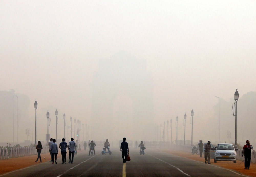 People walk in front of the smog covered India Gate war memorial in New Delhi, India, November 12, 2019. REUTERS/Anushree Fadnavis