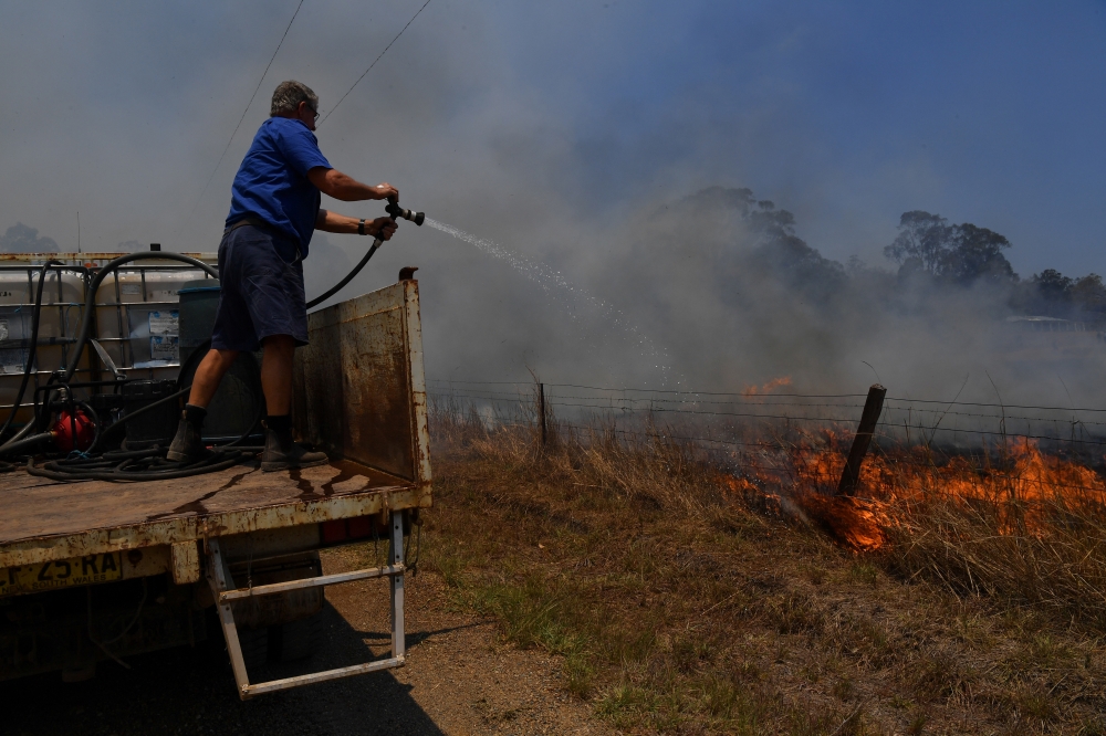 Tinonee resident Brian Acheson sets up his tip truck as a makeshift fire truck to assist residents fighting spot and grass fires in the Hillville area near Taree, NSW, Australia, November 13, 2019. AAP Image/Dean Lewins/via REUTERS 