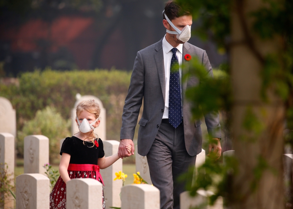Attendees wearing protective masks walk at Delhi War Cemetery before Britain's Prince Charles' visit to the cemetery in New Delhi, India, November 13, 2019. (REUTERS/Altaf Hussain)