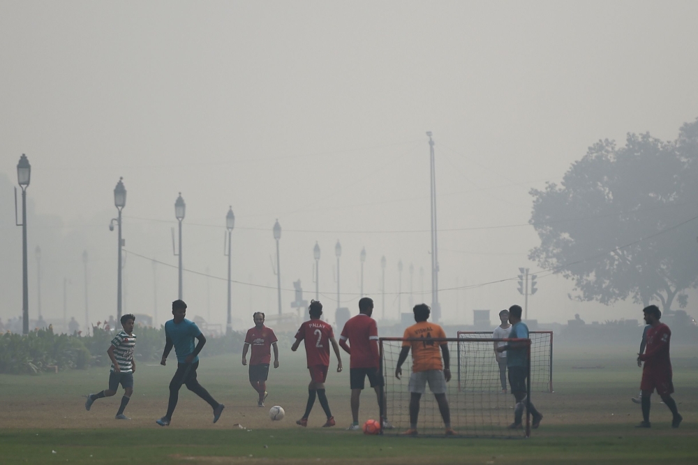 Youths play football near India Gate under heavy smog conditions in New Delhi on November 12, 2019. / AFP / Money Sharma 