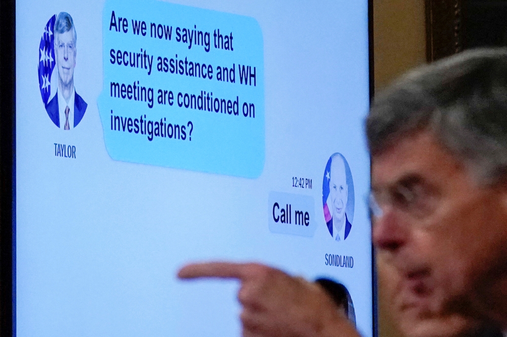 A text exchange between Ambassador Bill Taylor, charge d'affaires at the U.S. embassy in Ukraine, and U.S. Ambassador to the E.U. Gordon Sondland shows on a screen as Taylor (R) testifies before a House Intelligence Committee hearing as part of the impeac
