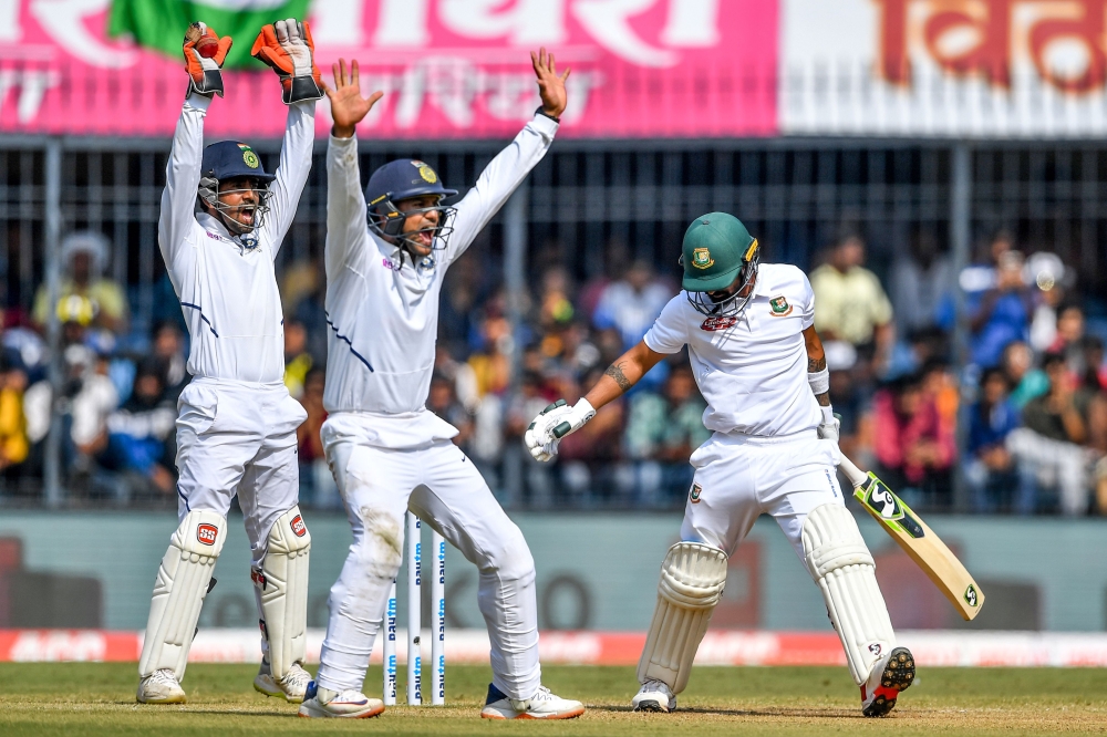 India's Wriddhiman Saha (L) and Mayank Agarwal (C) appeal unsuccessfully against Bangladesh's Liton Das (R) during the third day of the first Test cricket match of a two-match series between India and Bangladesh at Holkar Cricket Stadium in Indore on Nove