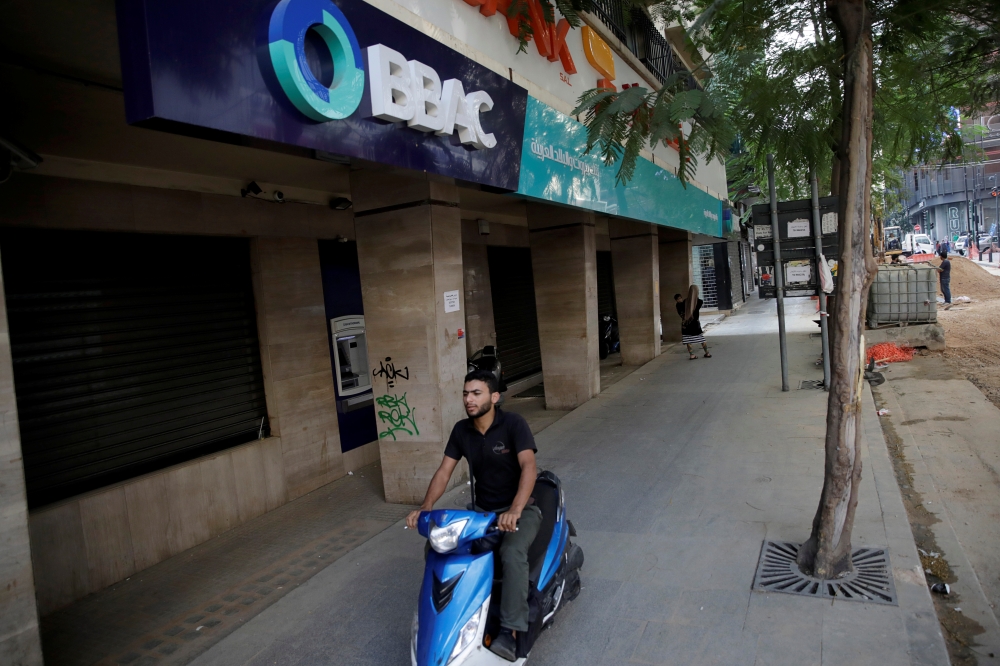 A man drives a motorbike past a closed bank office in Beirut, Lebanon November 15, 2019. Picture taken November 15, 2019. Reuters/Andres Martinez Casares