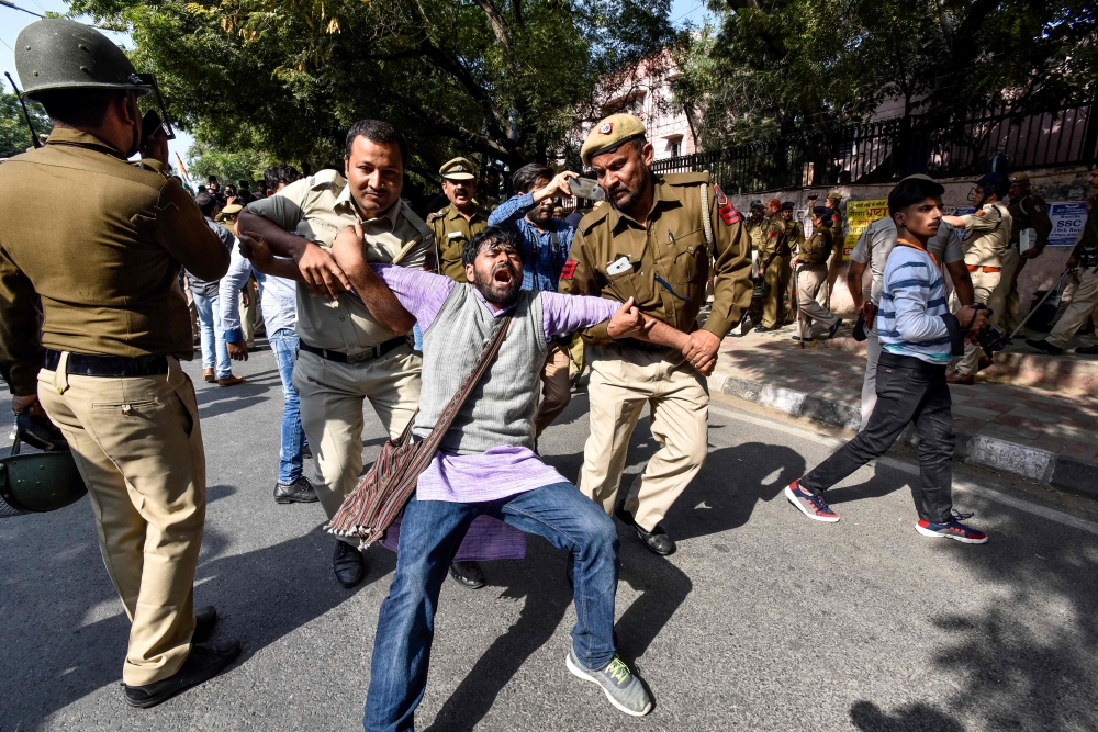 Security personnel hold a Jawaharlal Nehru University (JNU) student during a students protest against hostel fee hike, as security measures have been reinforced from JNU campus along the road to the march protest, in New Delhi on November 18, 2019. AFP / 