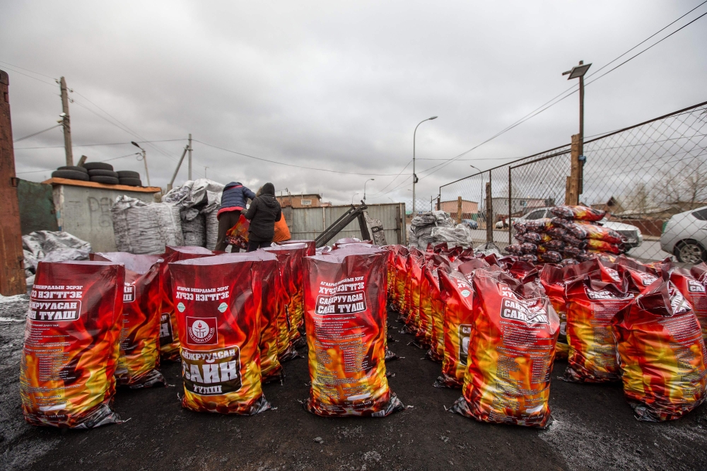 People packaging smokeless fuel at a sales spot in Ulaanbaatar, the capital of Mongolia, on October 19, 2019.  AFP / Byambasuren Byamba-Ochir 
