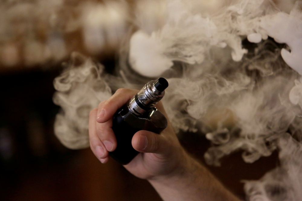 FILE PHOTO: A man holds an electronic cigarette as he vapes at a vape Shop in Monterrey, Mexico February 1, 2019. Picture taken February 1, 2019. FREUTERS/Daniel Becerril/File Photo
