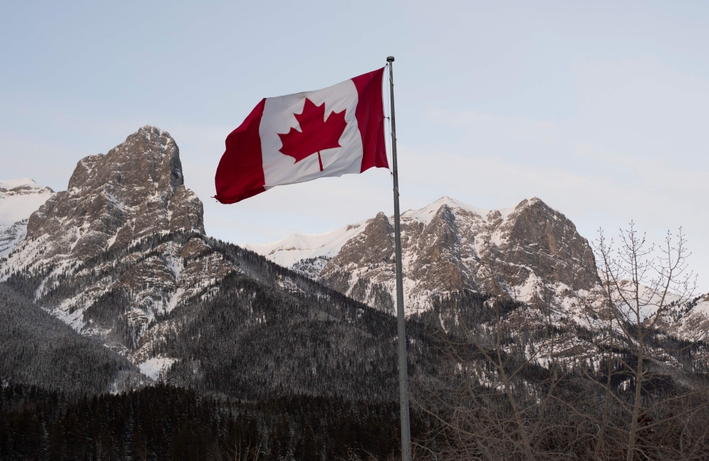 In this file photo taken on February 6, 2019 the Canadian flag flies over the Canadian Rockies at the Canmore Nordic Center in Canmore, Canada.  AFP / Don Emmert 
 
 