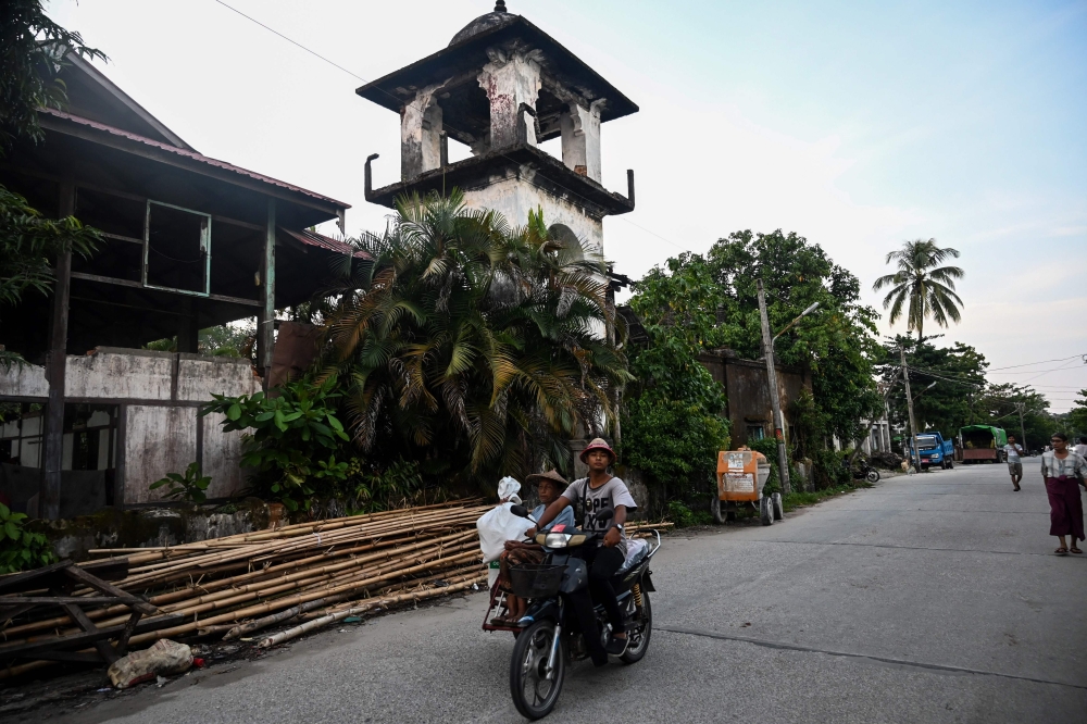 This October 3, 2019 photo shows a man driving his motorcycle past the ruins of a mosque in Kyaukphyu, Rakhine state, where Muslim residents have been forced to live in a camp for seven years after the inter-communal unrest tore apart the town. AFP / Ye A