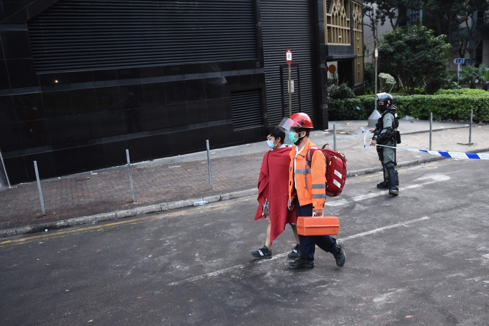 A medic leads a demonstrator to a waiting ambulance outside the campus of the Hong Kong Polytechnic University where dozens of pro-democracy protesters remain holed up inside, in the Hung Hom district of Hong Kong on November 21, 2019. AFP / Ye Aung Thu

