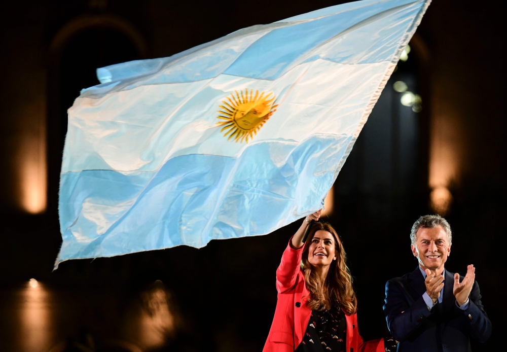 Argentine President Mauricio Macri applauds as First Lady Juliana Awada was a national flag during the closing rally of his campaign in Cordoba, Argentina, on October 24, 2019. AFP / Ronaldo Schemidt