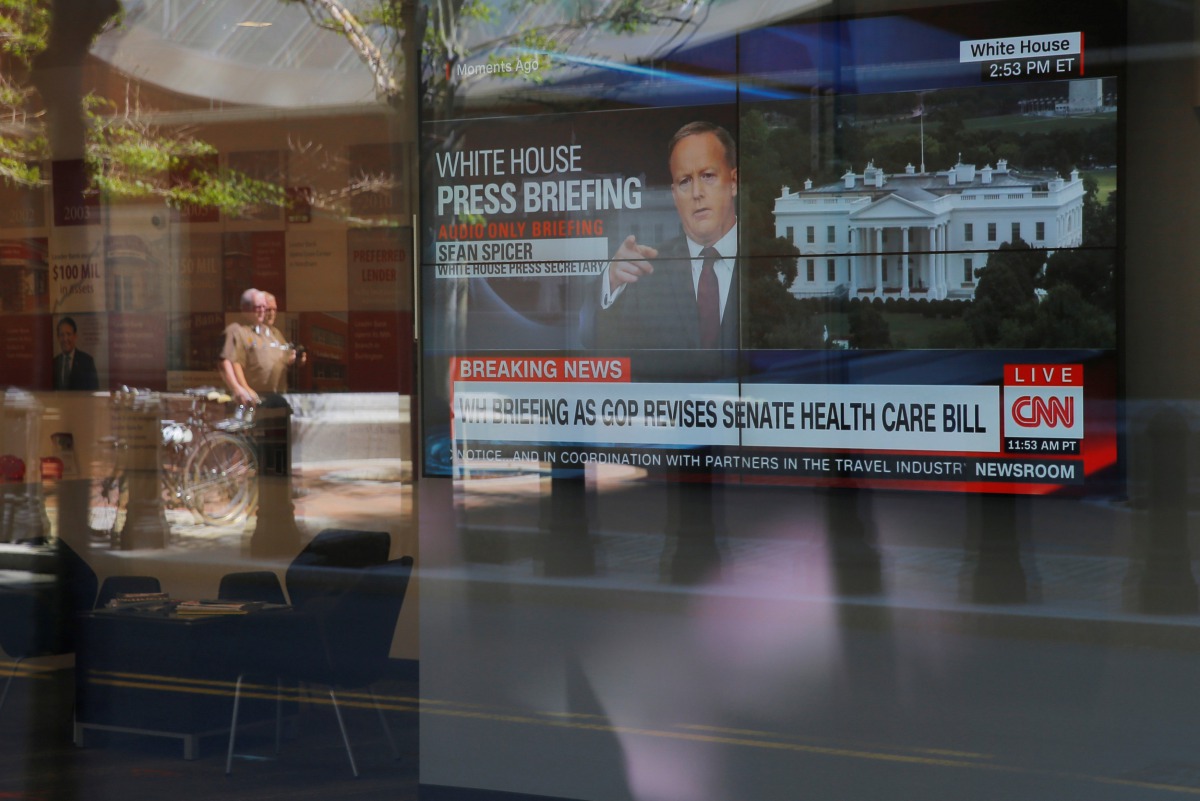 A large television in a bank shows CNN audio only broadcast of White House Press Secretary Sean Spicer's briefing in Boston, June 26, 2017. Reuters / Brian Snyder