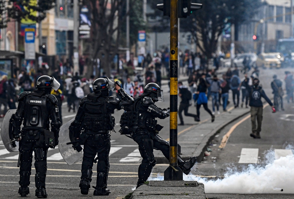 A riot policeman kicks a tear gas canister during a protest against the government of Colombia's President Ivan Duque, in Bogota, on November 23, 2019. AFP / Juan Barreto
 